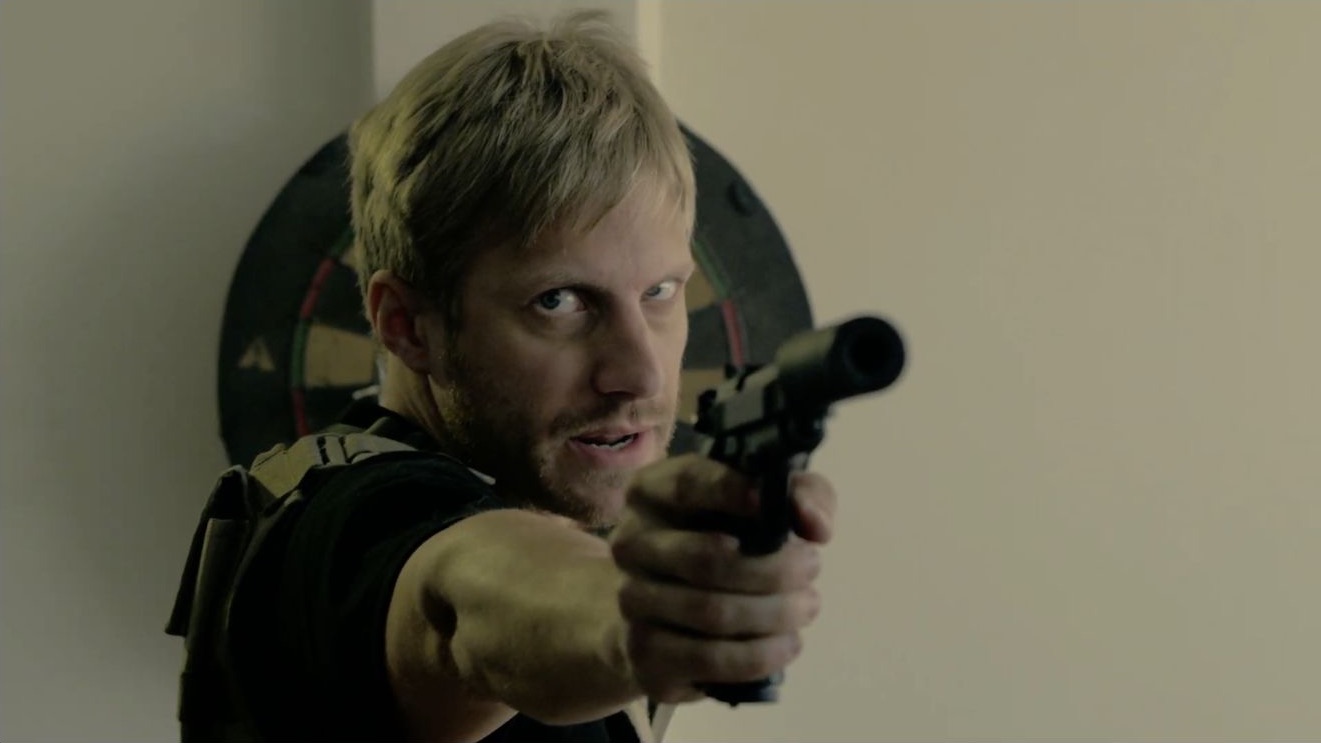 Close-up of an armed operative aiming a suppressed pistol in SYNC